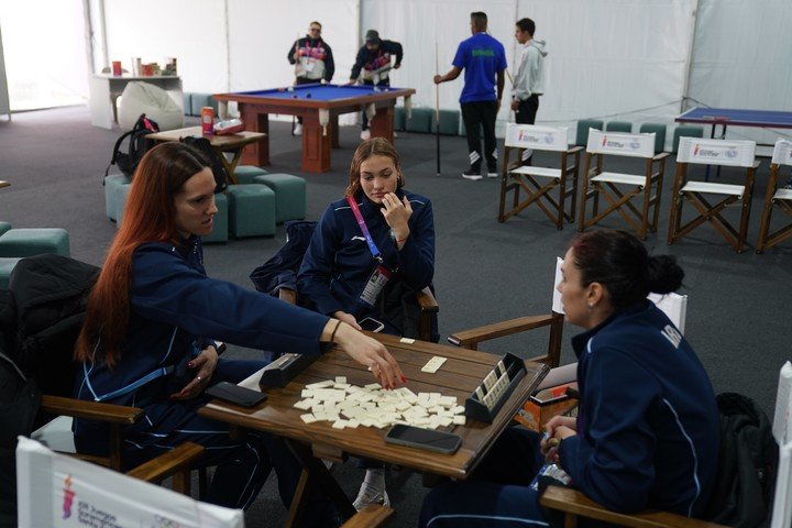 Las nadadoras argentinas enfocadas en un juego de mesa, mientras cerquita otros atletas juegan al pool. Foto Juano Tesone / Enviado Especial CLARIN
